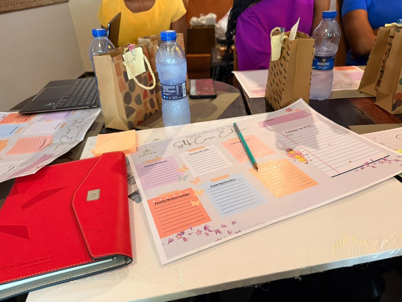 A self-care vision board worksheet and gift bags on the table